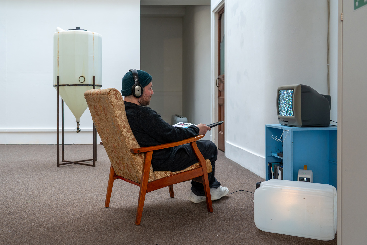 Visitor sits in a chair watching static on a television